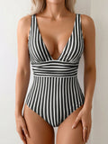 Woman wearing a black and white striped one-piece swimsuit with a deep V-neck and ruched waist.