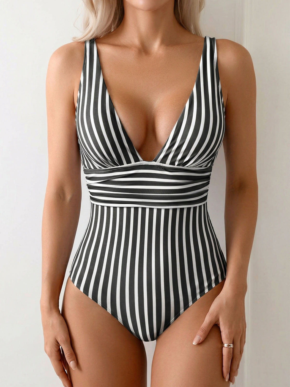 Woman wearing a black and white striped one-piece swimsuit with a deep V-neck and ruched waist.