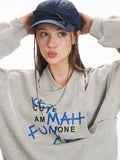 Headshot of a woman wearing a grey graphic print sweatshirt, showing the graphic print and the cut-out neckline detail.