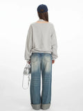 Rear view of a woman in a grey graphic print sweatshirt and distressed wide-leg jeans, showcasing the back of the garment.