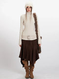 Woman wearing a cream ribbed knit turtleneck sweater, brown asymmetrical hem skirt, cream knit beanie, and brown suede boots.