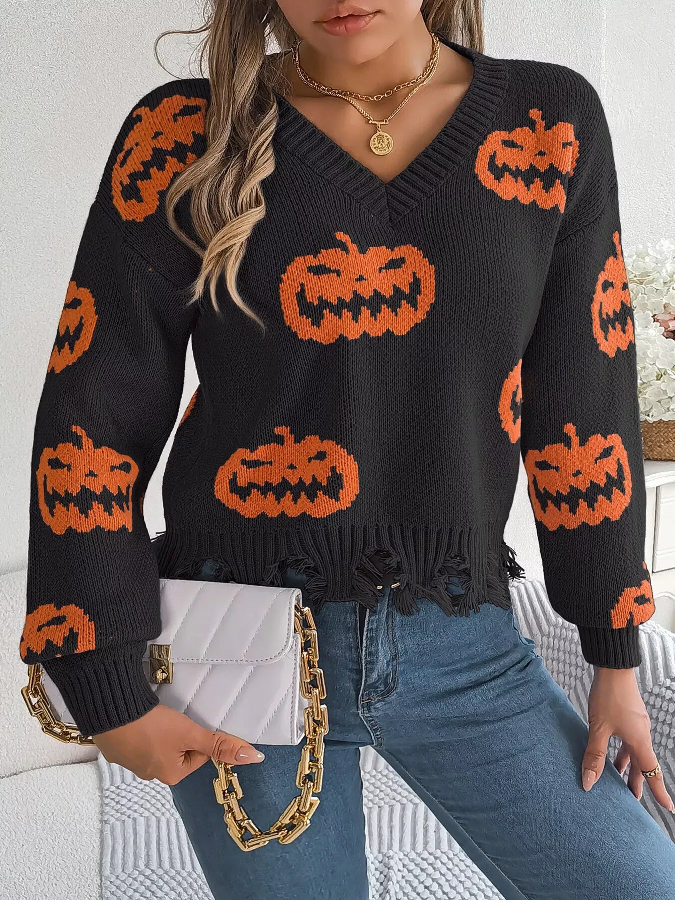 Woman in black knit sweater with orange pumpkins and distressed hem
