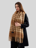 Woman in a black coat with a large plaid scarf wrapped around her neck