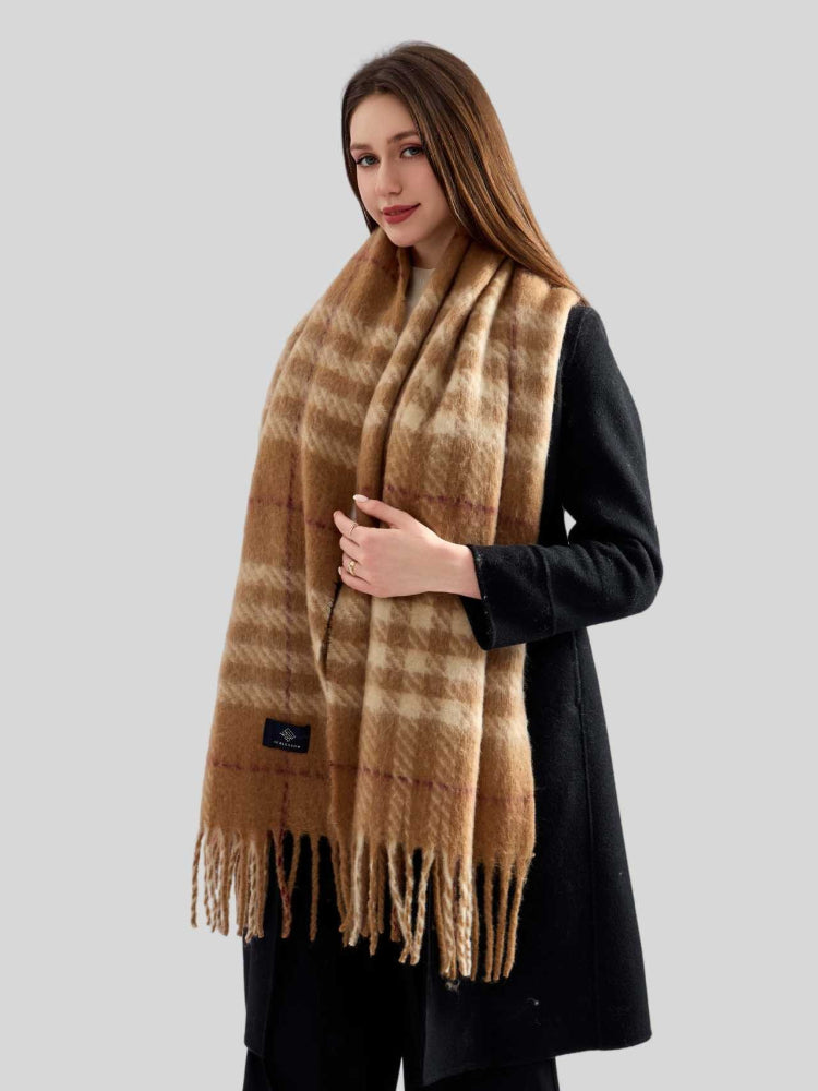 Woman in a black coat with a large plaid scarf wrapped around her neck