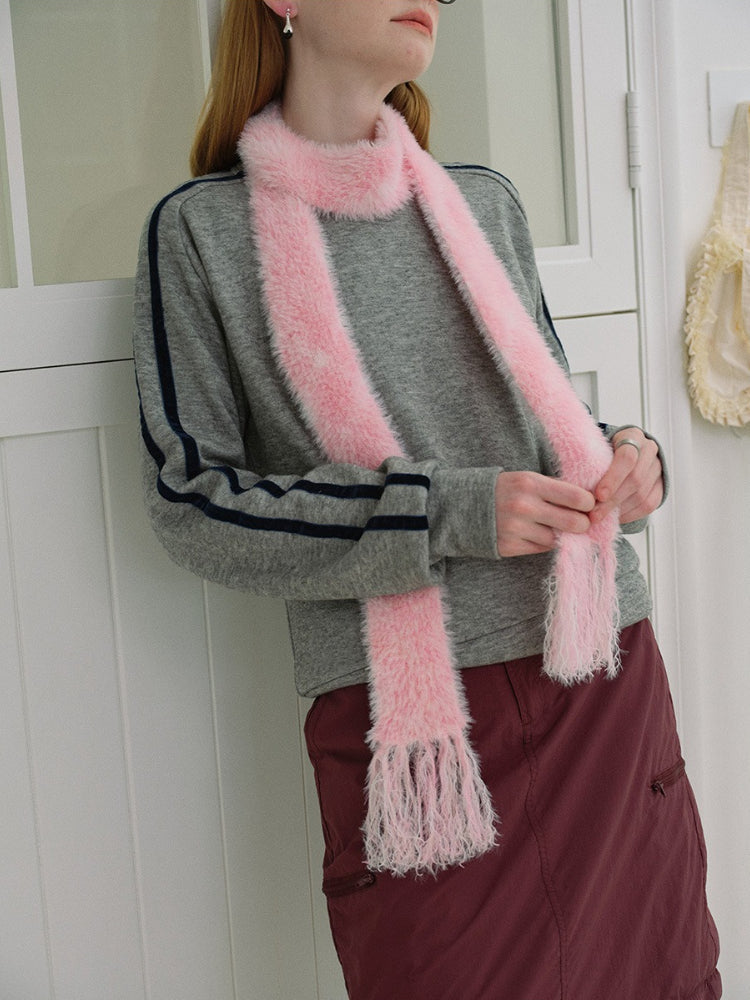 Woman wearing a gray sweatshirt, maroon skirt, white socks, black boots, and a pink fuzzy scarf with fringed ends.