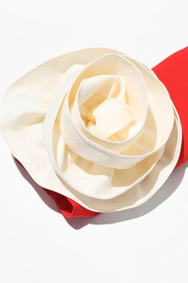 Close-up of white fabric rose embellishment on a red dress sleeve