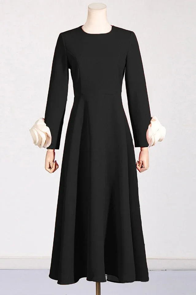 Black long-sleeved dress with white rose cuff embellishments on mannequin