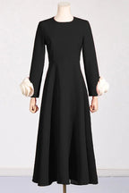 Black long-sleeved dress with white rose cuff embellishments on mannequin
