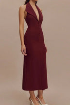 Side view of a woman in a burgundy sleeveless midi sheath dress with a deep V-neck, sharp collar, and button front detail.