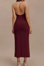 Rear view of a woman in a burgundy sleeveless midi sheath dress with a deep V-neck, sharp collar, and open back.
