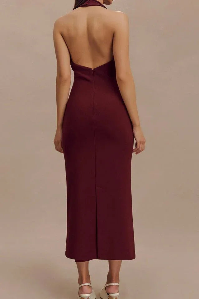 Rear view of a woman in a burgundy sleeveless midi sheath dress with a deep V-neck, sharp collar, and open back.