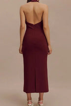 Back view of a woman in a burgundy sleeveless midi sheath dress with a deep V-neck, sharp collar, and open back.