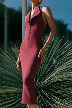 Woman wearing a burgundy sleeveless midi sheath dress with a deep V-neck, sharp collar, and button front detail, standing outdoors.