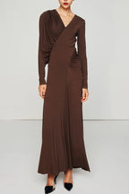 Woman wearing a long brown ruched V-neck dress with long sleeves.