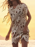 Woman wearing a cream openwork knit tunic with leaf-like cutouts and a scalloped hem