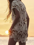 Back view of a woman in a cream openwork knit tunic at sunset
