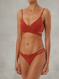 Terracotta wrap bikini top with double strap bottoms against a textured background