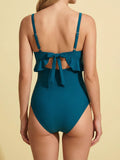 Woman in a teal one-piece swimsuit with a scoop neck, ruffled bust, and cut-out detail.