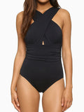 Woman wearing a black one-piece swimsuit with a criss-cross halter neckline and ruched waist detail