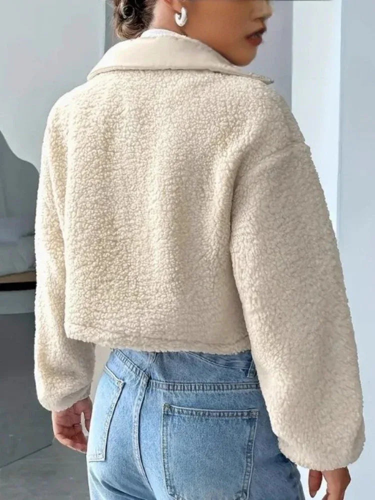Full body shot of a woman wearing a cream sherpa fleece cropped jacket.