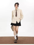 Woman walking in an oversized beige pinstripe button-down shirt, black skirt, and carrying a light beige handbag.