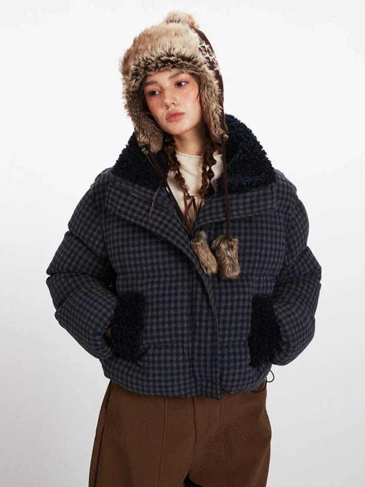 Front view of a woman in a cropped plaid puffer jacket with fur trim on the collar and cuffs, and a fur-lined hood.