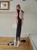 Woman adjusting her dark brown scarf over her pink cardigan.