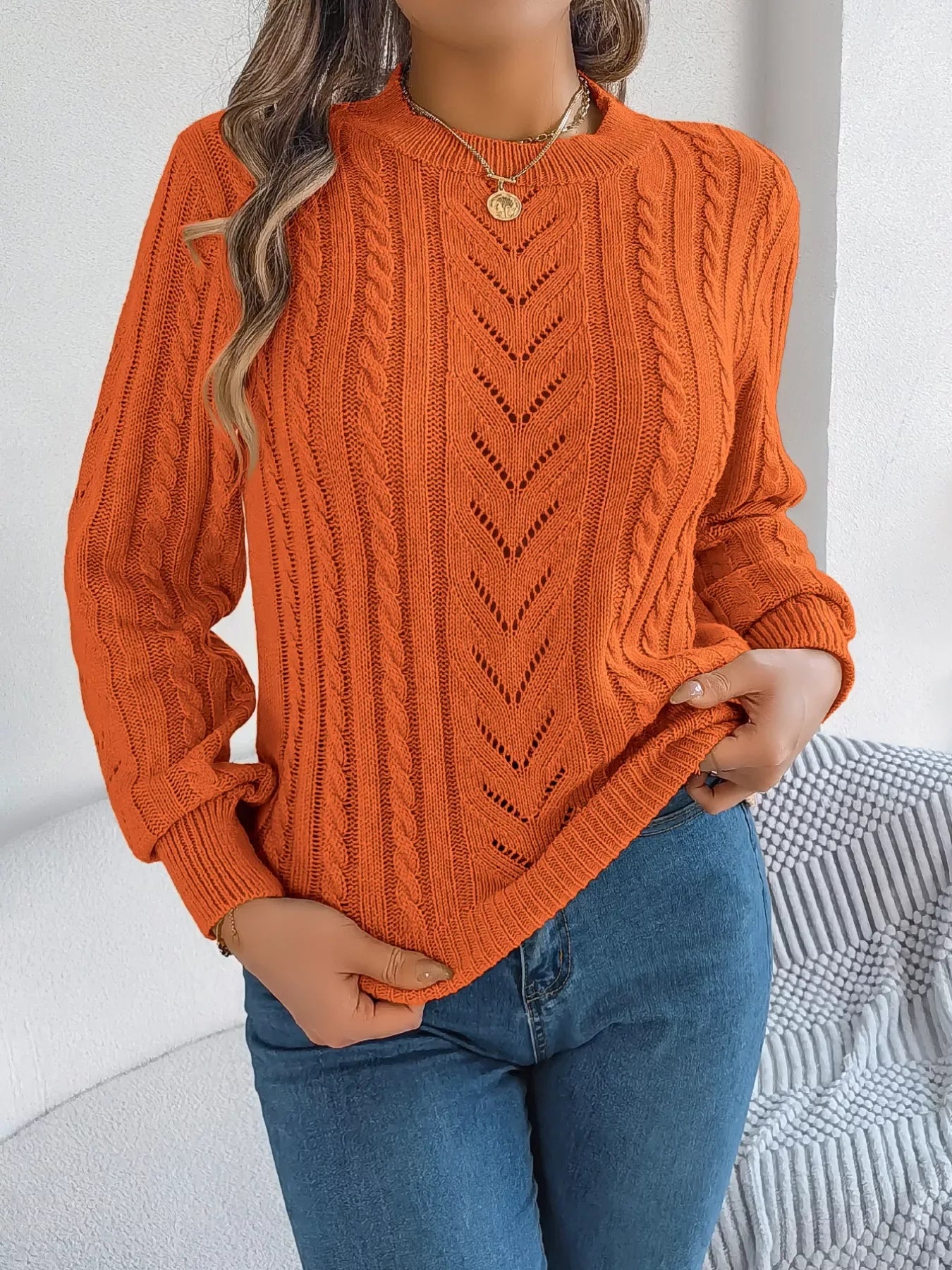 Woman wearing an orange cable knit crew neck sweater with openwork details and long sleeves. Main image