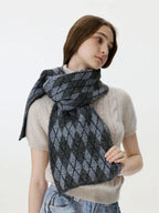 Woman adjusting a gray and black argyle knit scarf