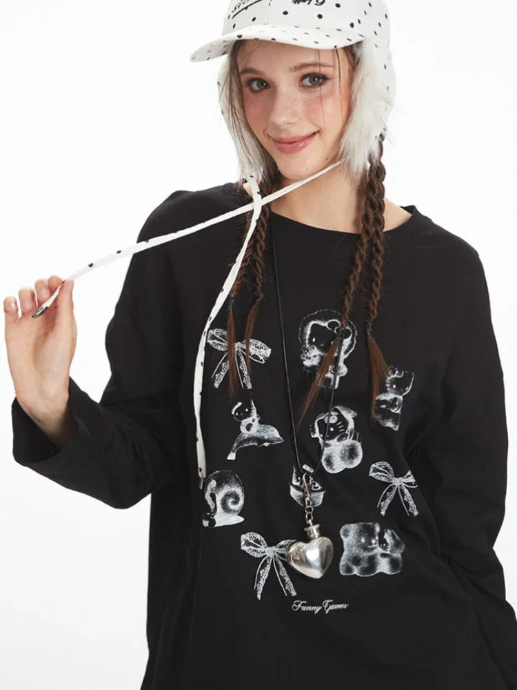 Close-up of a woman wearing a black long-sleeved graphic t-shirt, holding a drawstring.