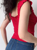 Side view of a woman wearing a red printed top with ruffled sleeves.