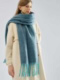Model styled with a blue textured scarf and a cream coat