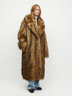 Woman wearing a long brown faux fur coat, hands in pockets.
