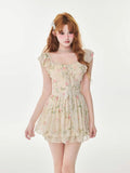Woman wearing a cream floral print chiffon mini dress with ruffle trim and a tie-front detail.