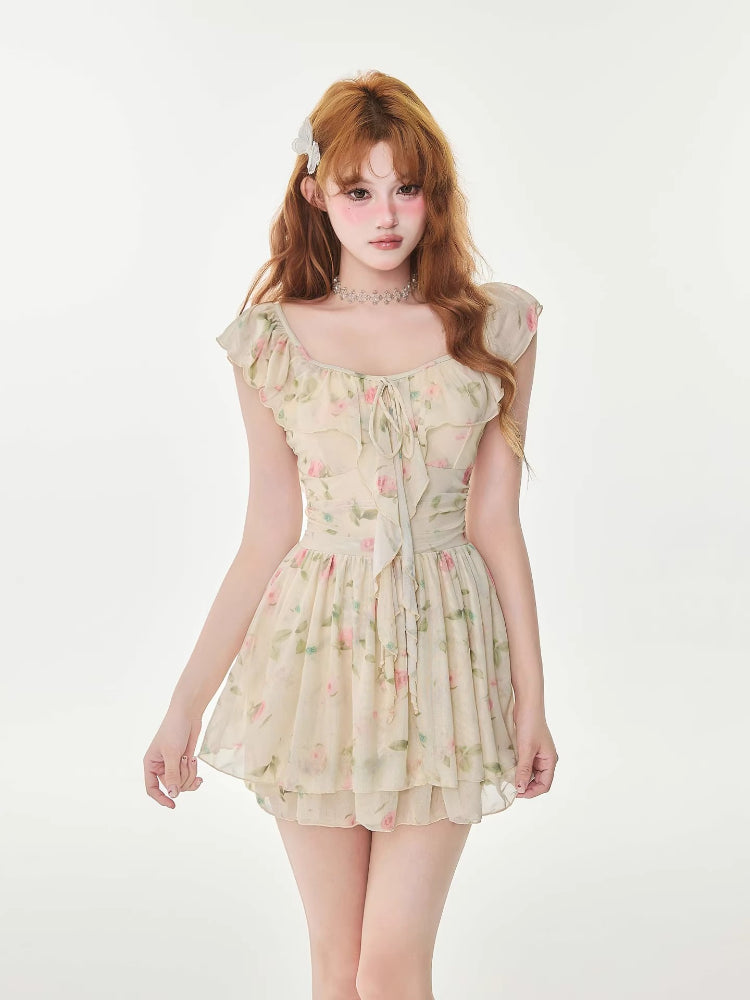 Woman wearing a cream floral print chiffon mini dress with ruffle trim and a tie-front detail.
