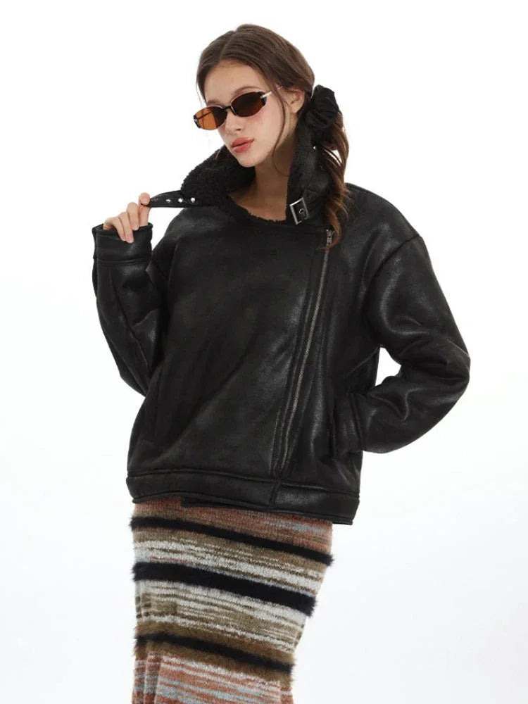 Close-up of a woman adjusting the lapel buckle of her black faux leather aviator jacket.