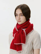 Close-up of a red wool blend scarf with decorative white stitching