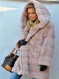 Woman wearing a light pink hooded faux fur coat with horizontal paneling.