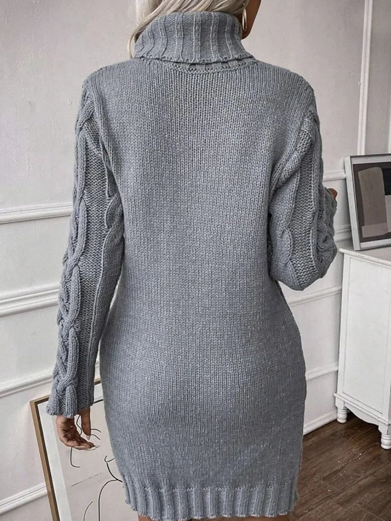 Woman wearing a grey cable knit turtleneck sweater dress with a belt