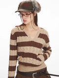 Front view of a woman wearing a brown and beige striped knit hooded sweater with a v-neckline and long sleeves, showing the pocket detail.
