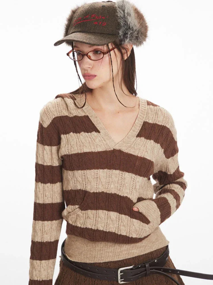 Front view of a woman wearing a brown and beige striped knit hooded sweater with a v-neckline and long sleeves, showing the pocket detail.