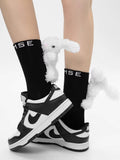 Black crew socks with a plush white bunny charm and 'MSE' logo, worn with black and white sneakers.