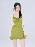 Woman wearing a green textured knit mini dress and a white open-knit cardigan with flared sleeves, styled with white lace-up sandals.
