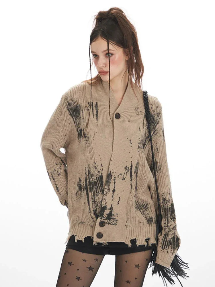 Model posing in a tan knit cardigan with abstract black print and distressed hem.