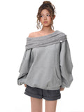 Model posing in a grey oversized sweatshirt with an off-the-shoulder neckline