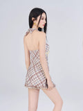 Rear view of a woman in a plaid halter dress with a tie front and ruffled hem.