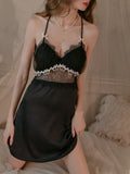 Model posing in a black satin chemise with lace trim