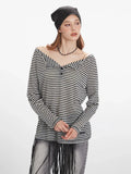 woman adjusting her black beanie while wearing a black and white striped long-sleeve shirt
