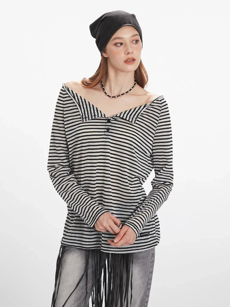 woman adjusting her black beanie while wearing a black and white striped long-sleeve shirt