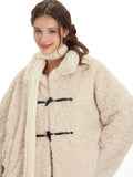 Woman posing in a cream fleece toggle coat and white scarf